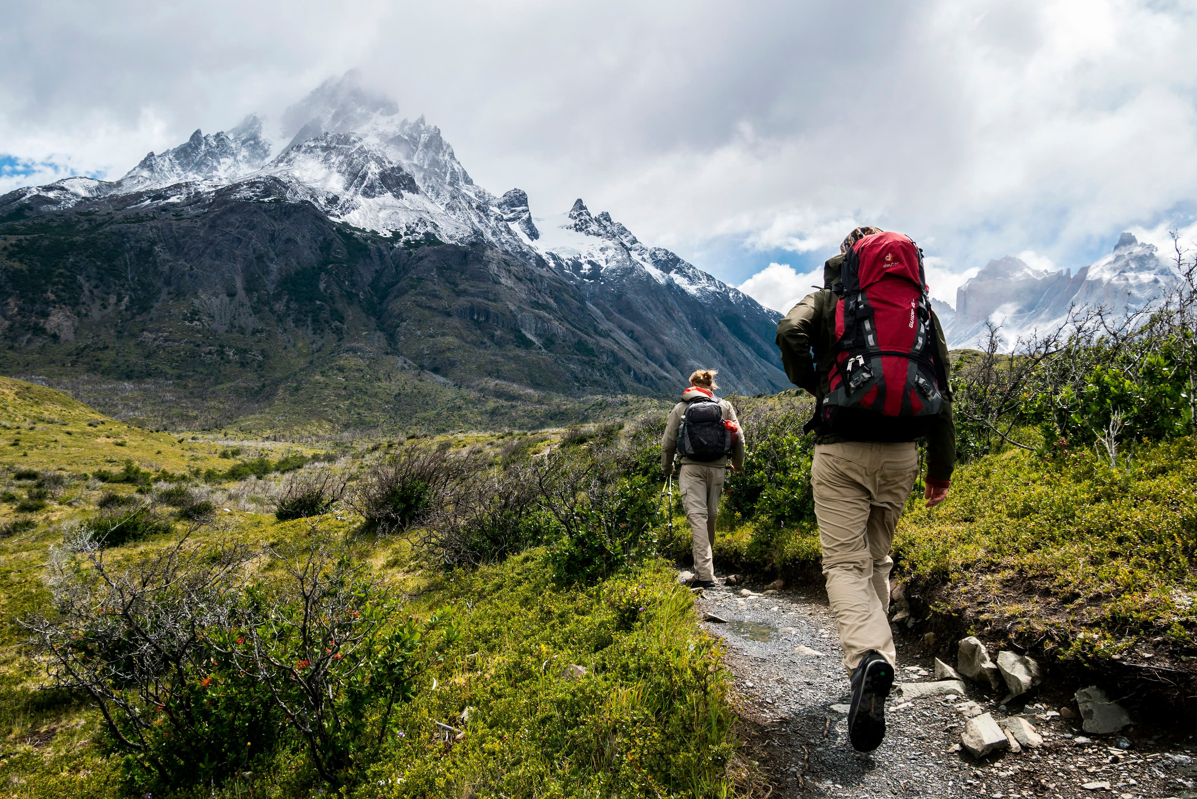 Deux randonneurs de dos, sac au dos, sur un sentier de montagne.
